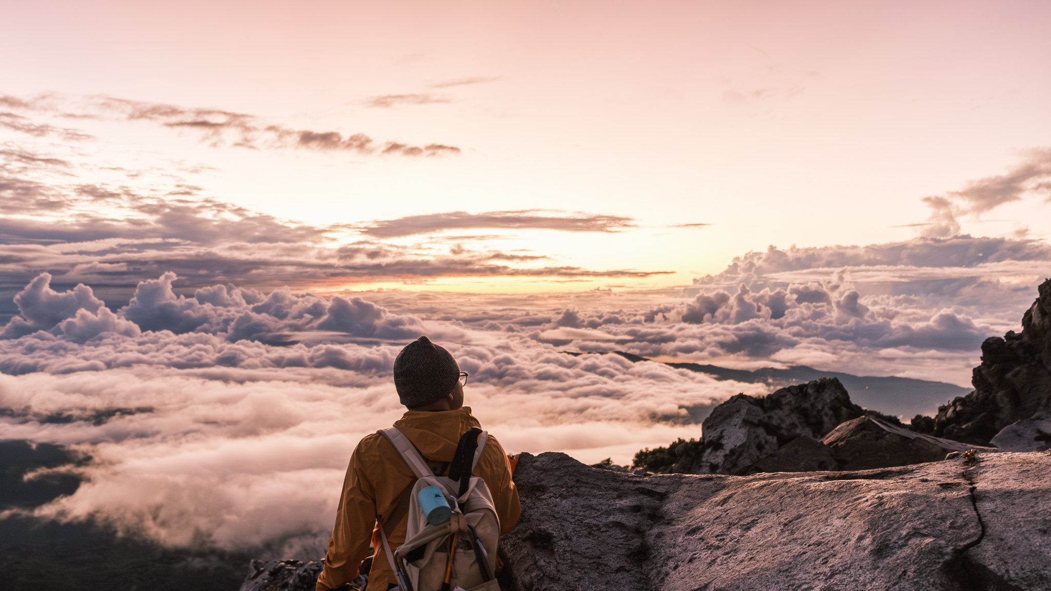 A hiker looking at the sunrise of Mt. Apo at the Boulder Face