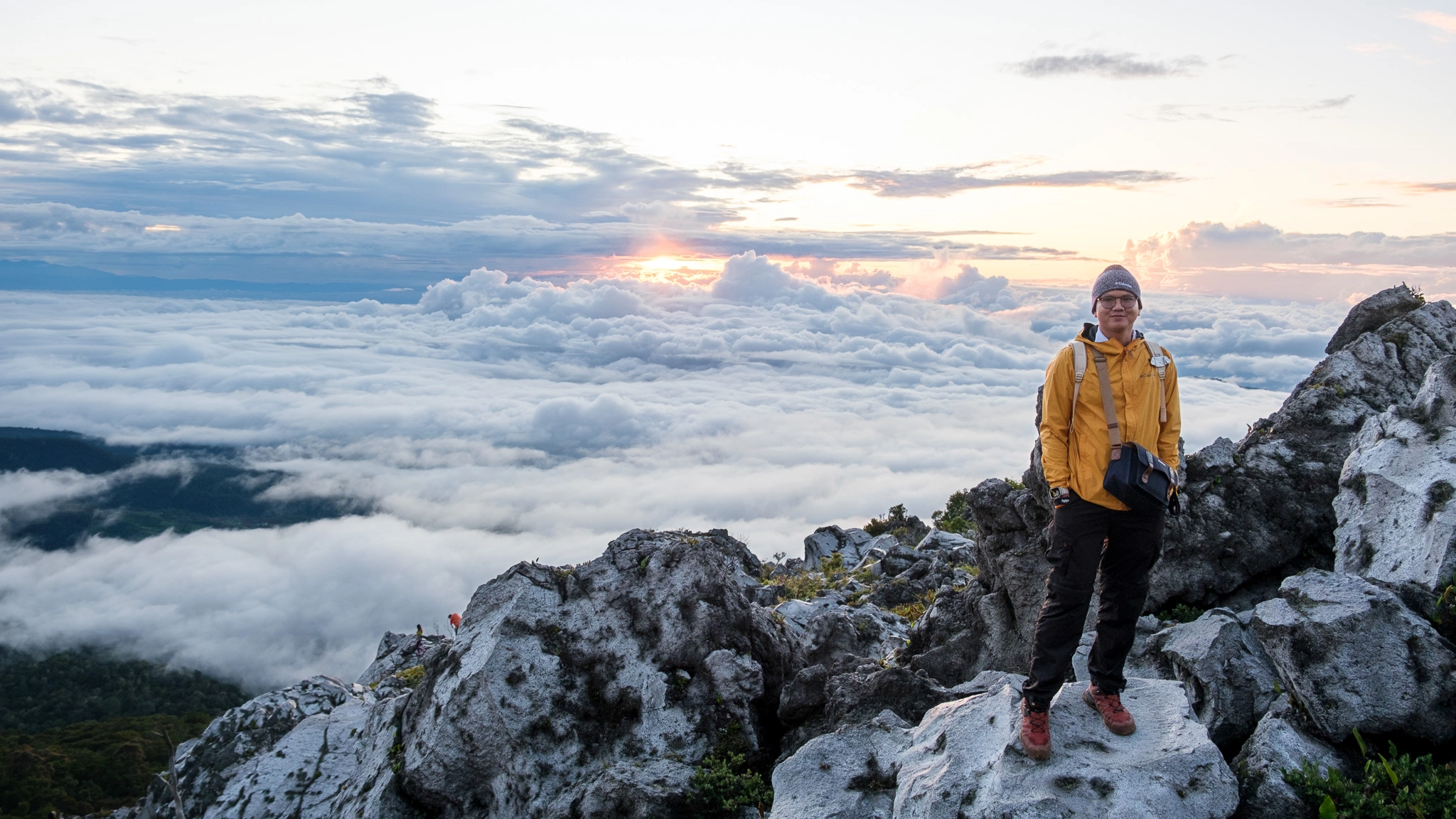 A hiker standing at a rock with sea of clouds on his background at Mt. Apo Boulder Face