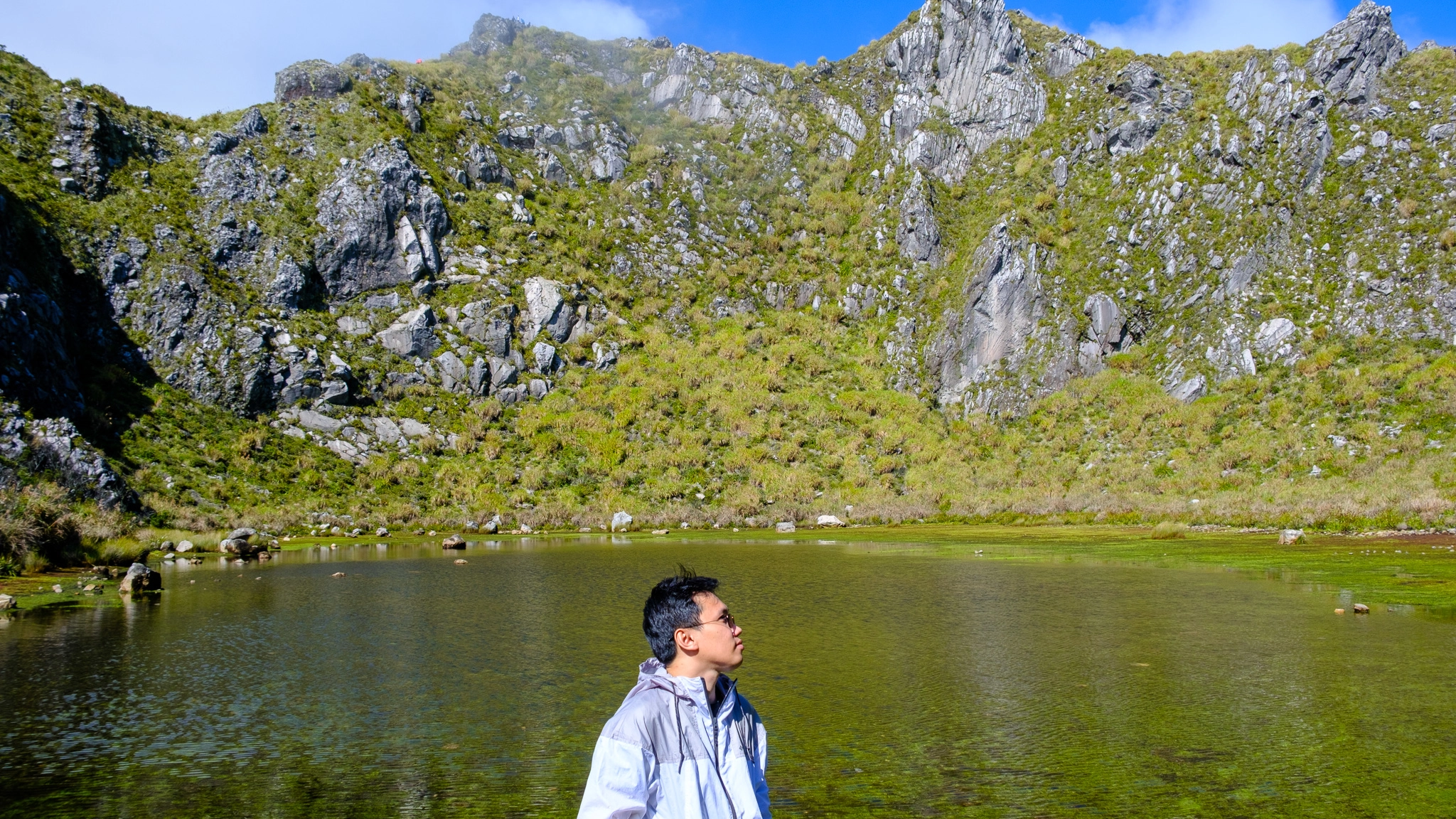 A hiker standing near the Mt. Apo summit with the crater lake as its background