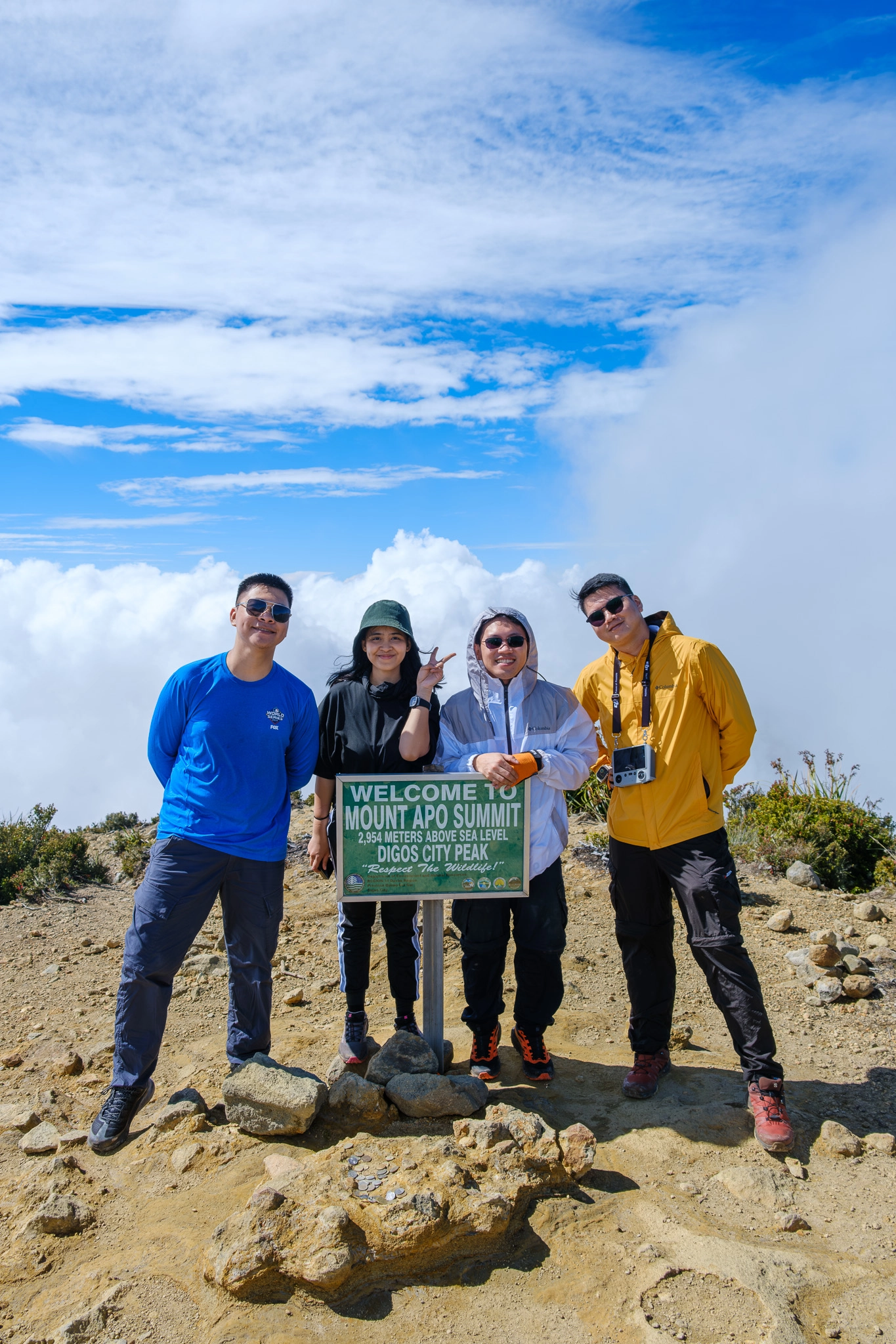 A group of hikers smiling at the Mt. Apo summit sign