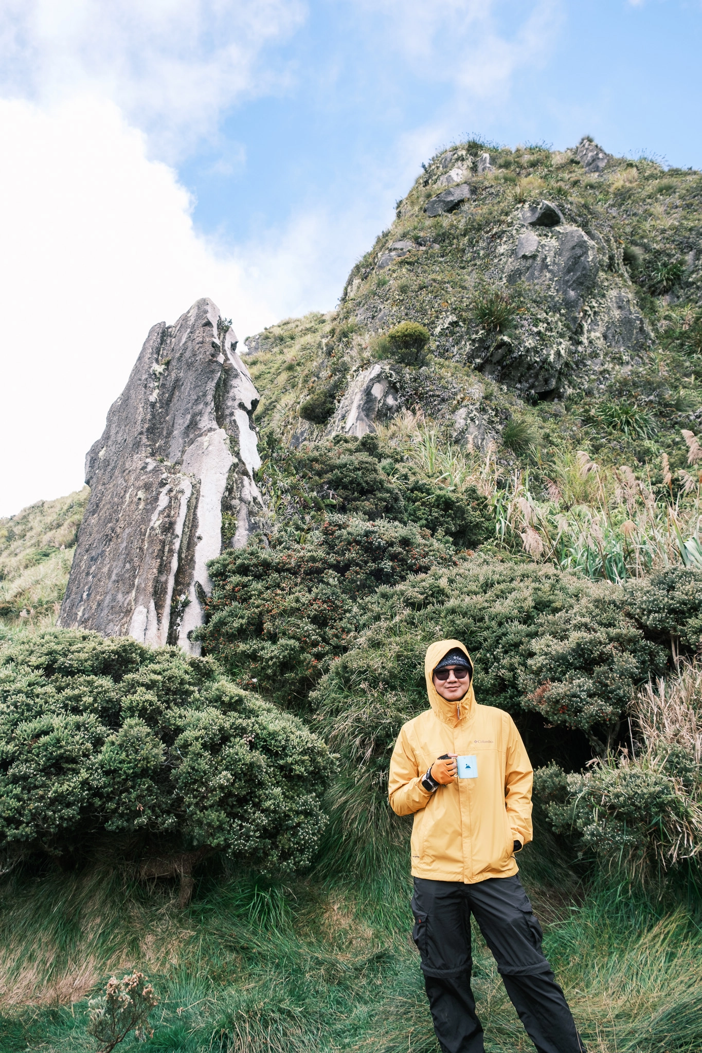 A hiker drinking coffee, smiling at the old campsite of Mt. Apo