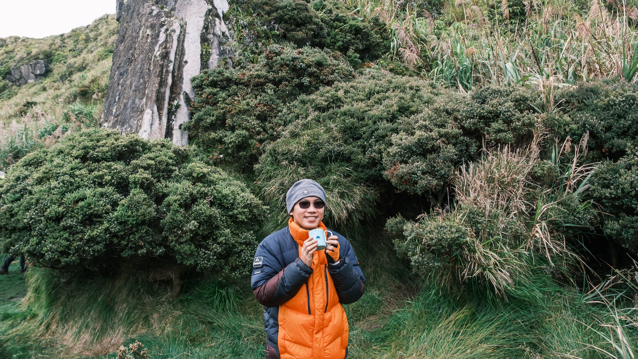 A hiker drinking coffee, smiling at the old campsite of Mt. Apo