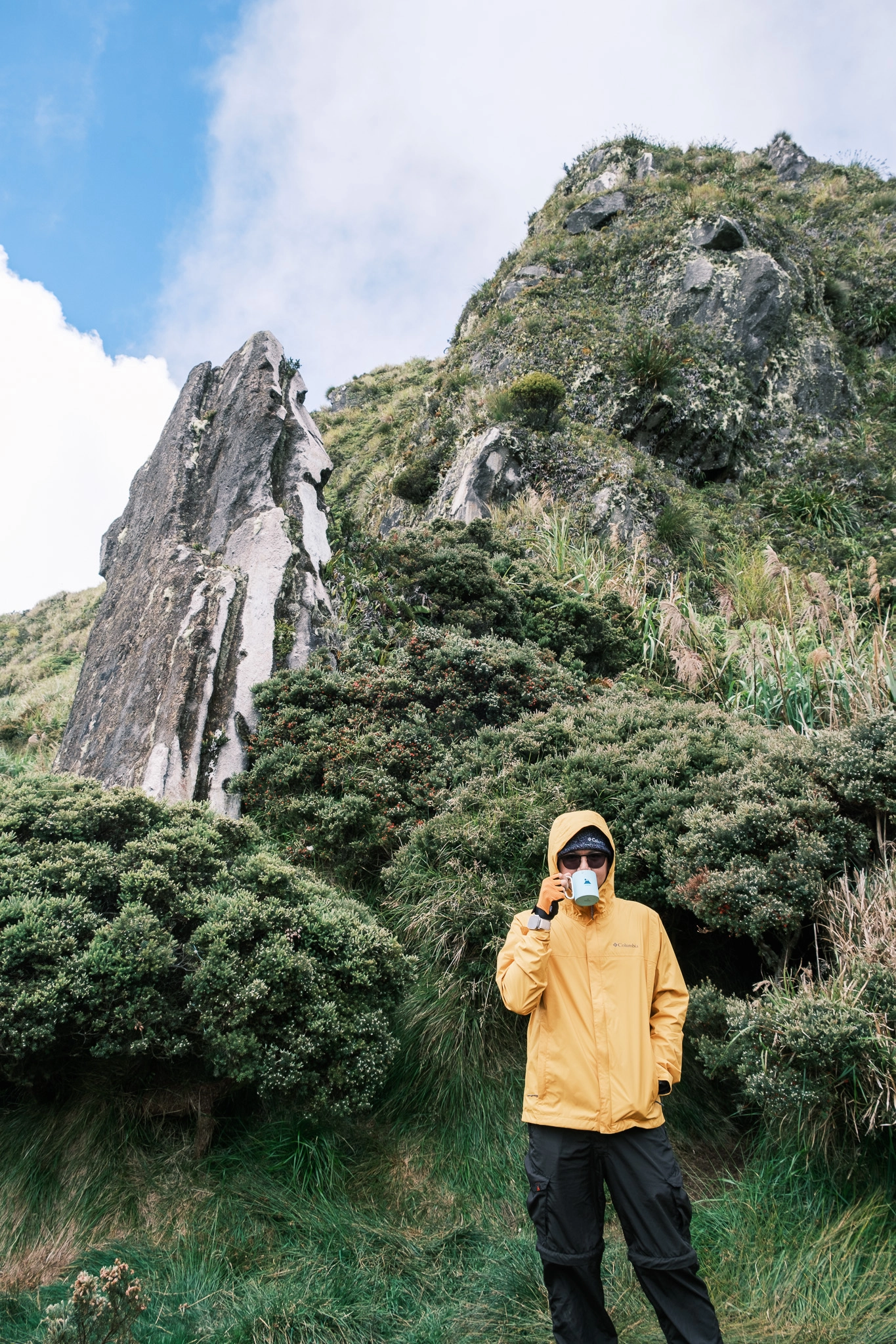 A hiker drinking coffee, smiling at the old campsite of Mt. Apo