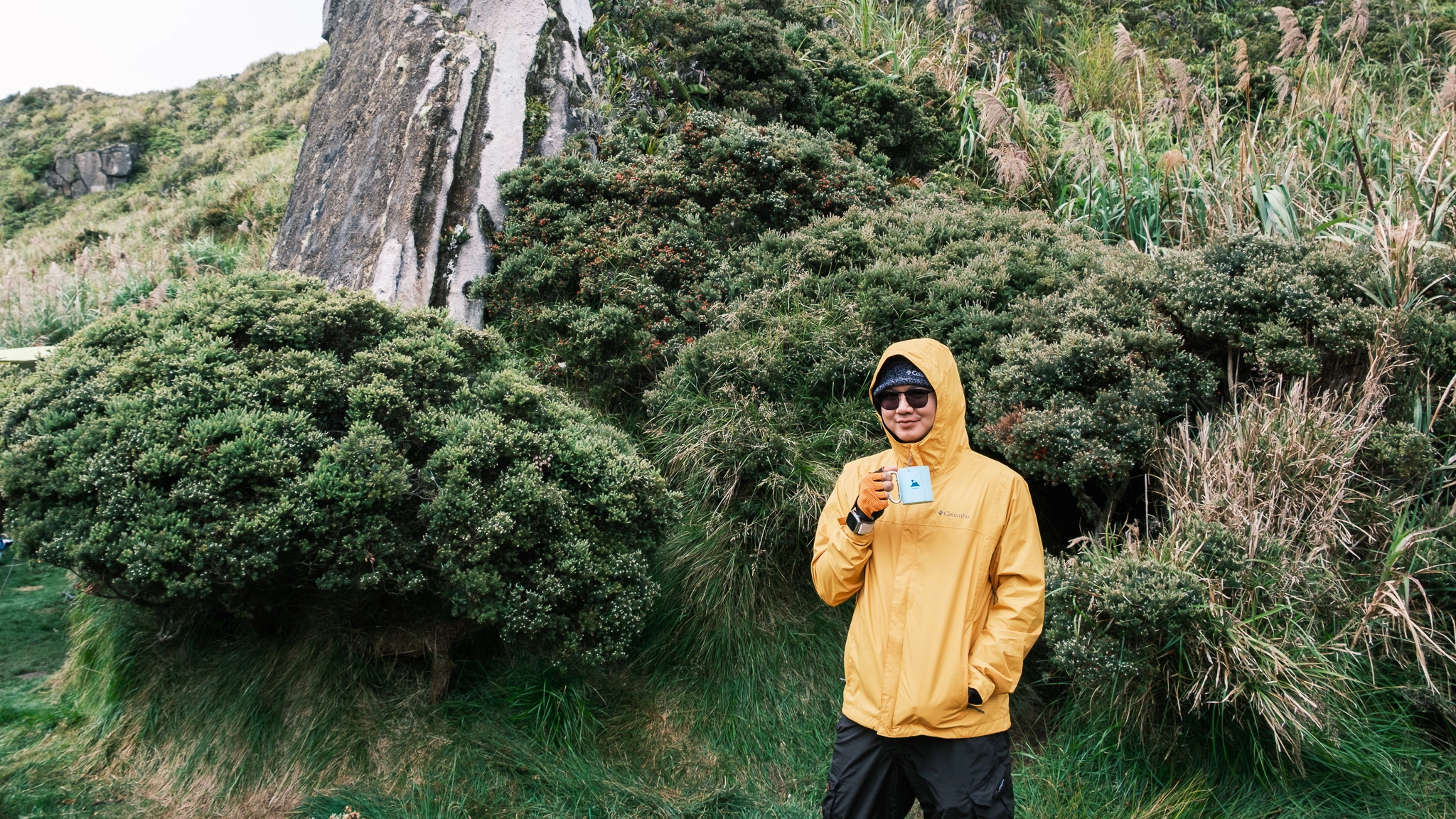 A hiker drinking coffee, smiling at the old campsite of Mt. Apo